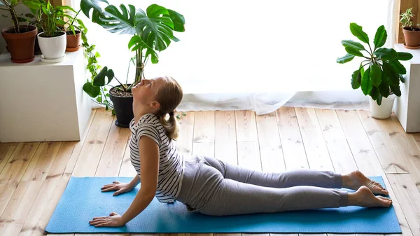 Maradj otthon. álarcos nő jógázik a nappaliban a karantén alatt — Stock Fotó