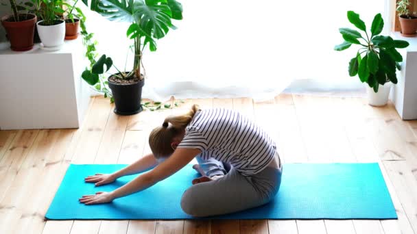 Rămâi acasă. femeie mascată care face yoga în camera de zi în timpul carantinei — Videoclip de stoc