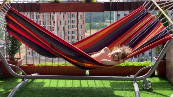 Descansar en la ciudad. niño descansando en una hamaca en la terraza — Vídeos de Stock