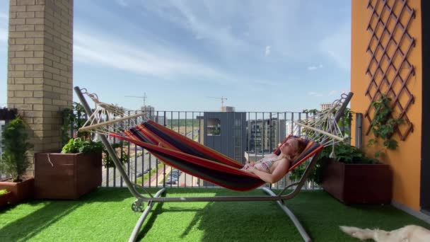 在城市里休息。穿比基尼的女人在阳台上的吊床上放松 — 图库视频影像