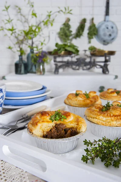 Provence tarzı mutfakta, etli börek bir tepsi ve kekik bir sprig masada. Neredeyse bulaşıkvar. Beyaz tuğla duvarın yanında bir sandık var. Üzerinde çiçekler ve yeşillikler ile ölçekler ve vazolar vardır.