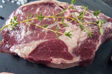 Sıcak yatıyor için gri bir stand üzerinde mermer biftek ve tuz dökülür. Etin üzerinde kekik bir sprig olduğunu.