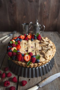 Taze çilek ile dekore edilmiş berry cupcake ahşap bir masa üzerinde duruyor. Çatal bıçak takımı serildi. Gümüş kahve demliği ve sütçü arkasında.