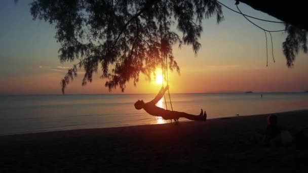Ευτυχισμένος Άνθρωπος Ταλαντεύεται Μια Κούνια Μια Παραλία Sunset — Αρχείο Βίντεο