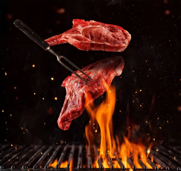 Domuz parçaları uçan yukarıda siyah arka plan üzerine izole ızgara ızgara biftek pirzola. Gıda, çok yüksek çözünürlüklü görüntü uçan kavramı