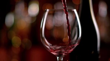 Şişeden kadehe kırmızı şarap doldurmanın süper yavaş bir yolu. 4K çözünürlüklü, yüksek hızlı sinema kamerasıyla çekildi..