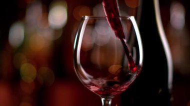 Şişeden kadehe kırmızı şarap doldurmanın süper yavaş bir yolu. 4K çözünürlüklü, yüksek hızlı sinema kamerasıyla çekildi..