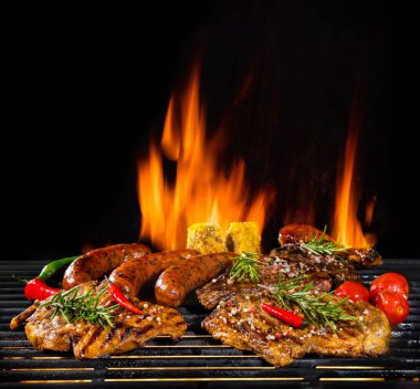 Delicious pieces of meat on grill with Fire flames. Isolated on black background. Barbecue and grilling. Very high resolution image clipart