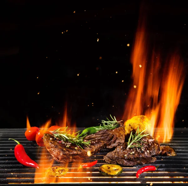 火の炎で焼きでおいしい牛肉ステーキ 黒の背景上に分離 バーベキュー グリルします 非常に高解像度画像 — ストック写真