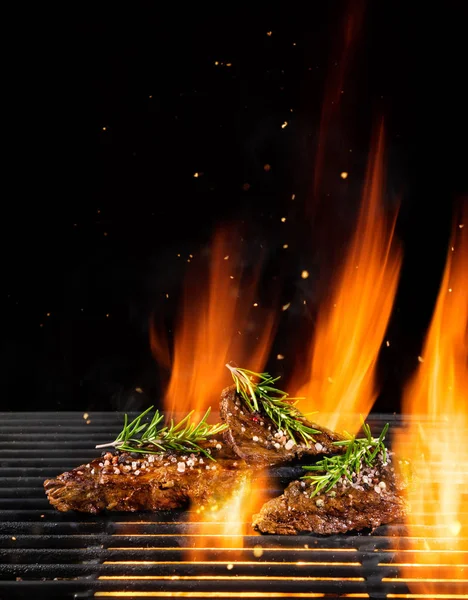 火の炎で焼きでおいしい牛肉ステーキ 黒の背景上に分離 バーベキュー グリルします 非常に高解像度画像 — ストック写真