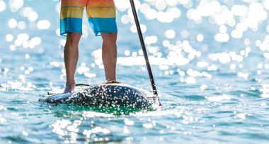 Genç adam paddleboard üzerinde ayakta detayını. Paddleboarding ulaşım ve su aktivite spor modern yoludur.
