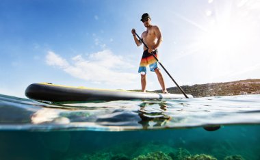 Genç adam paddleboard, yarısı altında ve yarım yukarıdaki su kompozisyon. Paddleboarding ulaşım ve su aktivite spor modern yoludur.