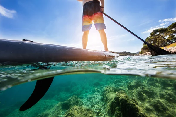 Genç adam paddleboard, yarısı altında ve yarım yukarıdaki su kompozisyon detayını. Paddleboarding ulaşım ve su aktivite spor modern yoludur.