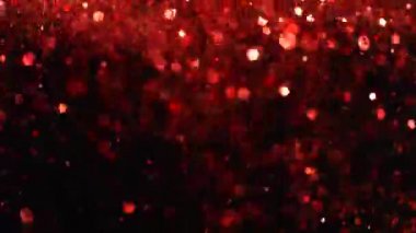Siyah arka plan üzerine süper ışıltılı, yavaş kırmızı parçacıklar. Odak sığ derinliği. Yüksek hız sinema Kamerası, 1000 fps üzerinde filme.