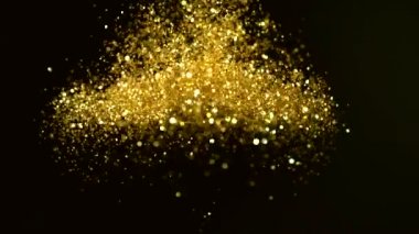 Siyah zemin üzerinde ışıldayan altın parçacıkların süper yavaş çekimi. Sığ odak derinliği. Yüksek hızlı sinema kamerası, 1000 fps..