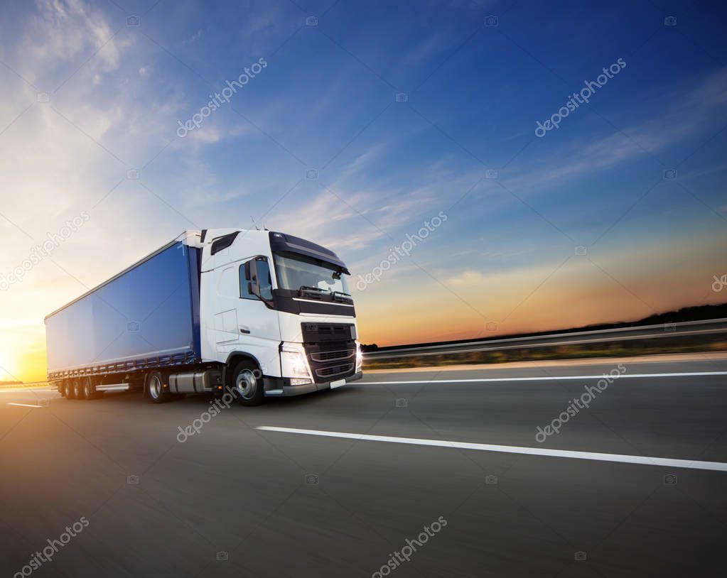 Loaded European truck on motorway in beautiful sunset light. On the road transportation and cargo.