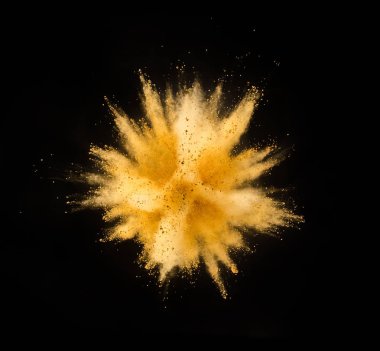 Explosion of yellow powder isolated on black background. Abstract colored background clipart