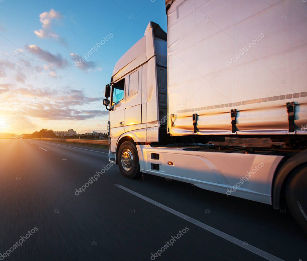 Loaded European truck on motorway in beautiful sunset light. On the road transportation and cargo.