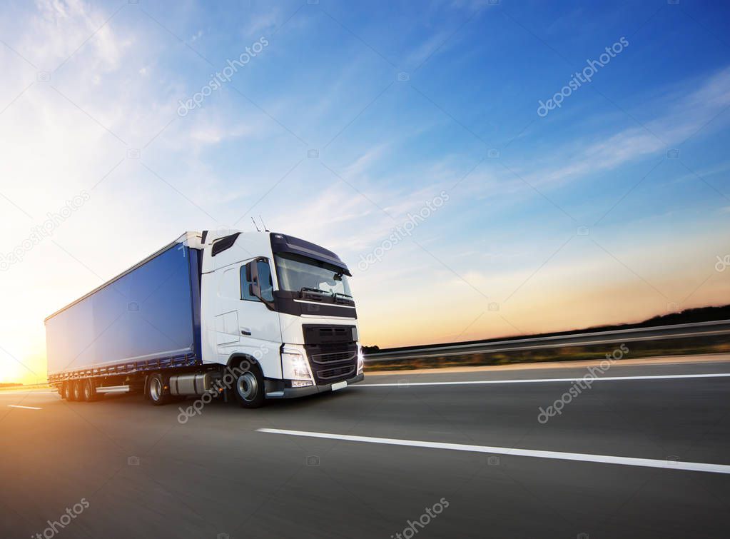 Loaded European truck on motorway in beautiful sunset light. On the road transportation and cargo.