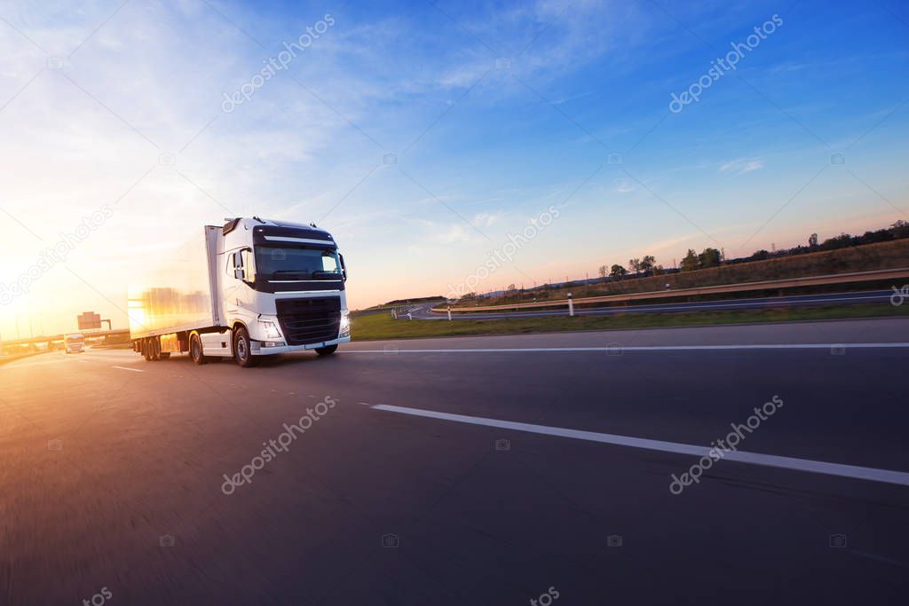 Loaded European truck on motorway in beautiful sunset light. On the road transportation and cargo.