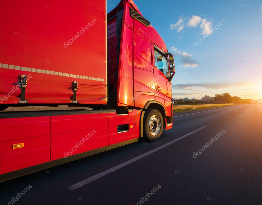 Loaded European truck on motorway in beautiful sunset light. On the road transportation and cargo.