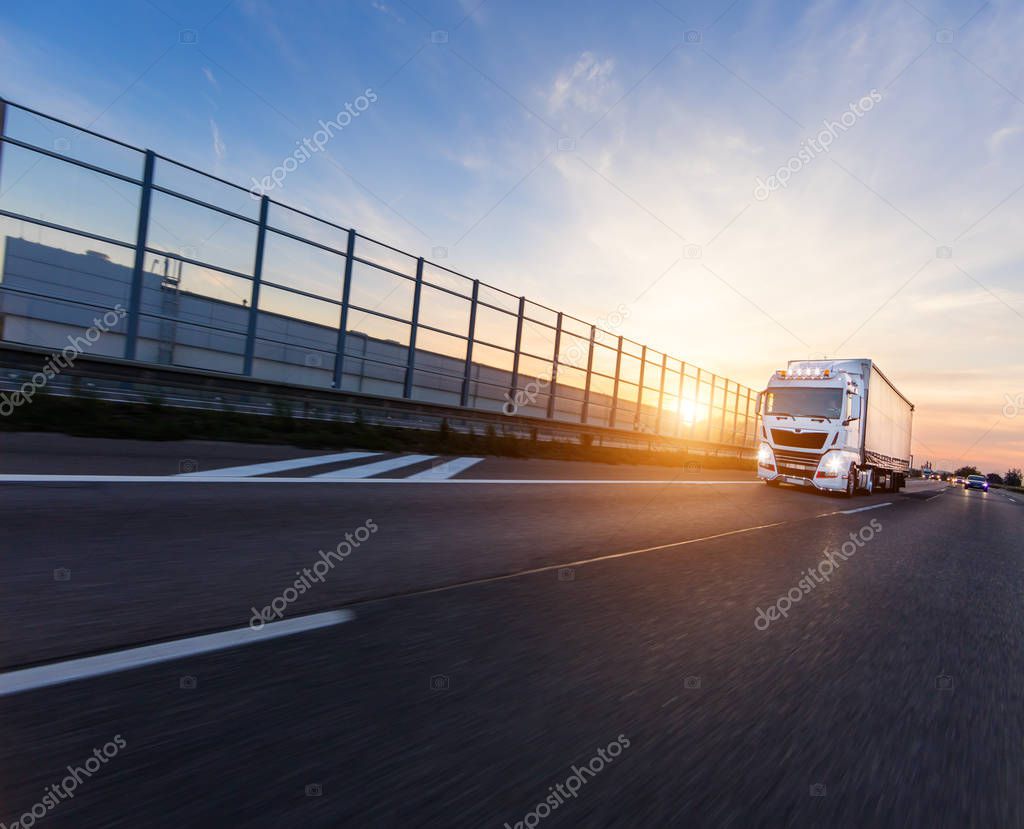 Loaded European truck on motorway in beautiful sunset light. On the road transportation and cargo.
