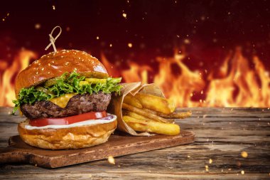Lezzetli hamburger tahtaya hizmet arka planda, ateşle. Metin için boş alan