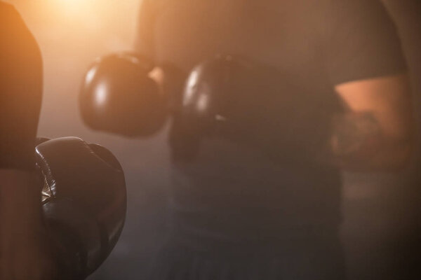 Detail of men boxing gloves during training lesson. Dark industrial fitness workout interior with cinematic atmosphere. Active sport and healthy lifestyle.