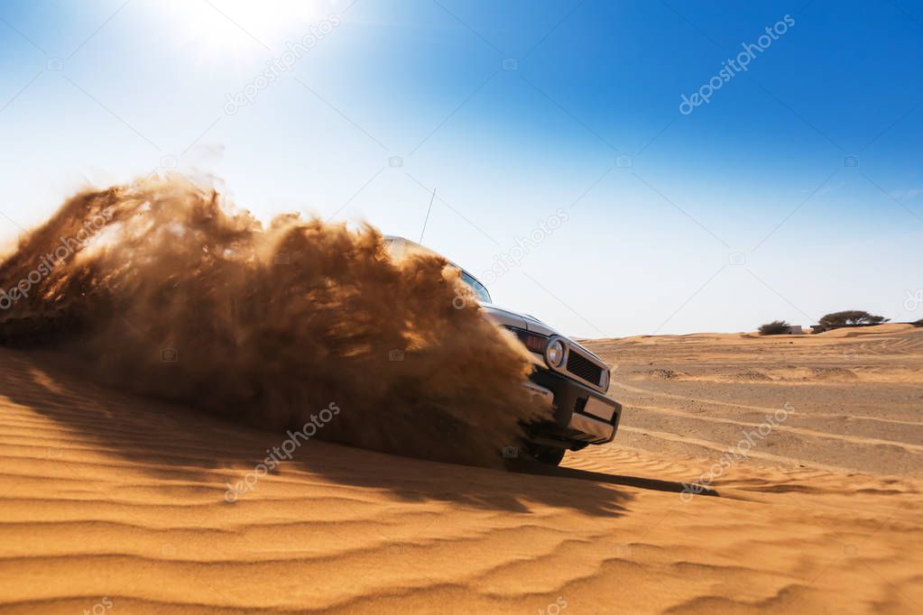 Drifting offroad car 4x4 in desert. Freeze motion of exploding sand powder into the air. Action and leasure activity.