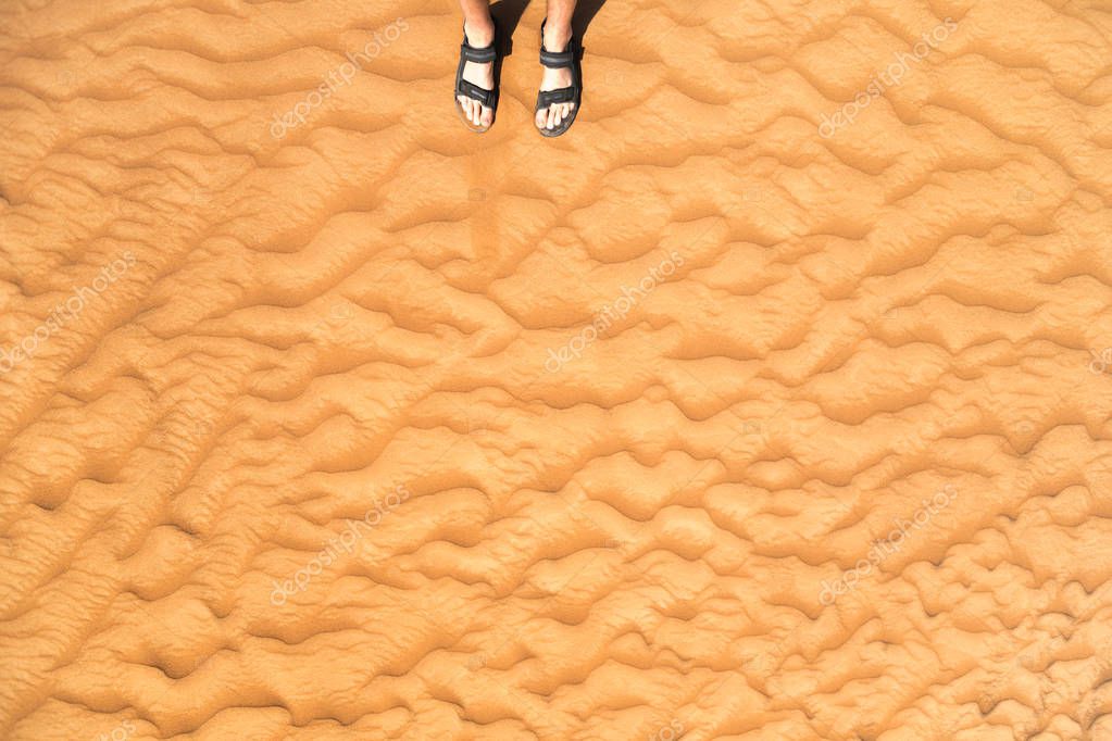 Detail of man legs with sandals on sandy dunes in desert