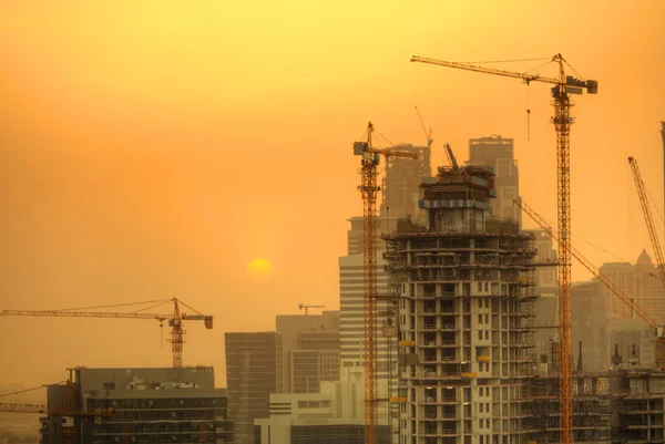 Construction zone with cranes building skyscrapers in sunset light. New and modern architecture building structure in Dubai city, UAE.