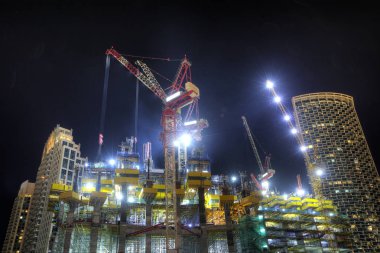 Gökdelenler ve geceleri vinçler ile inşaat alanı. Dubai city, Birleşik Arap Emirlikleri yapısında bina yeni ve modern mimari.