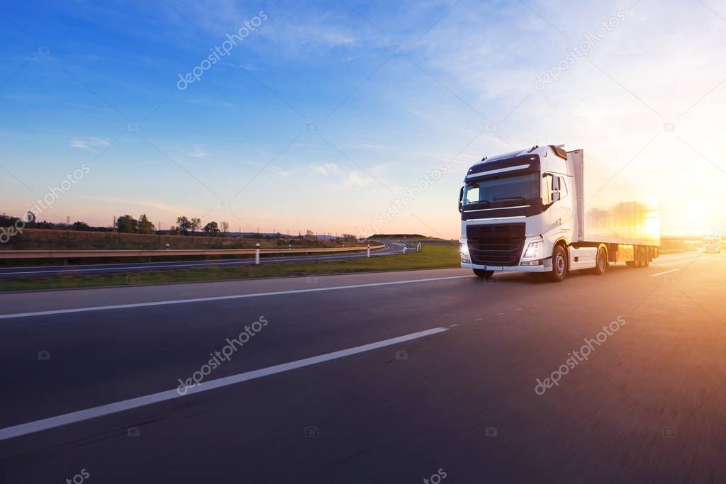 Loaded European truck on motorway in beautiful sunset light. On the road transportation and cargo.