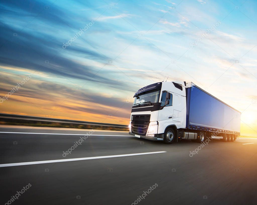 Loaded European truck on motorway in beautiful sunset light. On the road transportation and cargo.