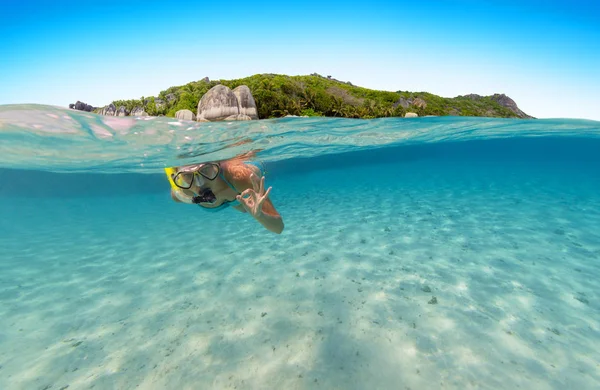 シュノーケ リングの女性の水表面のビューの上と下 水中の動植物 海洋生物及び背景にエキゾチックな島 — ストック写真