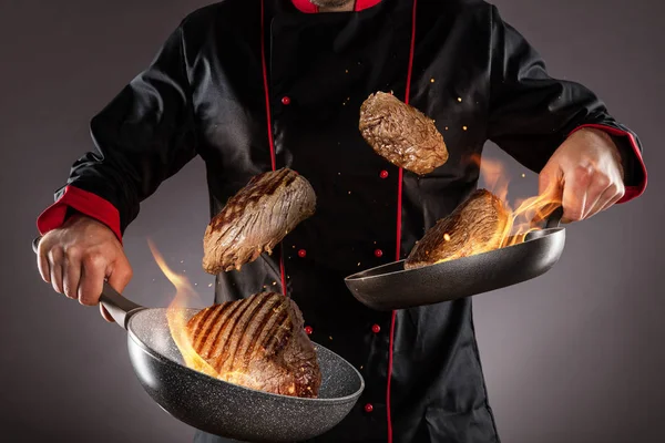 Gros plan du chef jetant des steaks de bœuf dans les airs — Photo