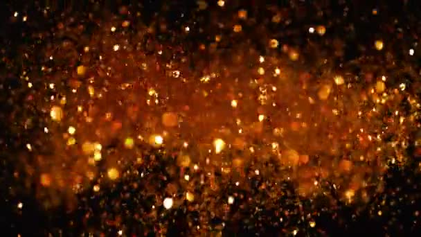 Mouvement super lent de particules dorées scintillantes sur fond noir. Faible profondeur de mise au point. Filmé sur caméra de cinéma à grande vitesse, 1000 images par seconde.