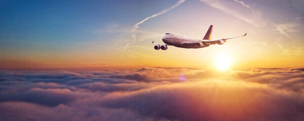 Commercial airplane flying over dramatic sunset