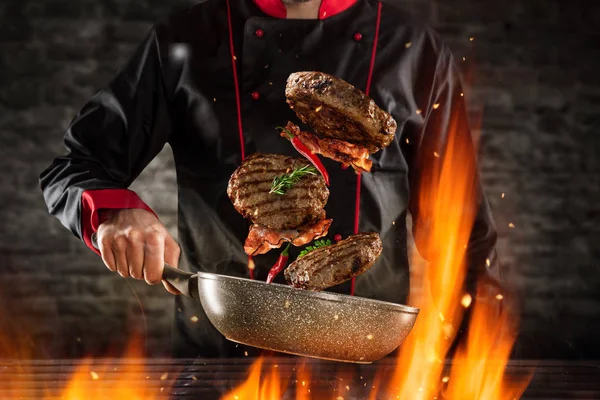 Closeup of chef throwing hamburger steaks — Stock Photo, Image