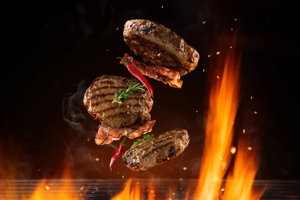 Flygande nötkött hamburgare bitar ovanför burning grill — Stockfoto