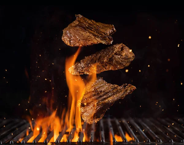 Bifes de carne de vaca voadora acima da grelha em chamas — Fotografia de Stock