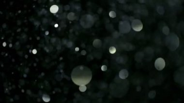 Siyah arka plan üzerine süper ışıltılı, yavaş gümüş parçacıkları. Odak sığ derinliği. Yüksek hız sinema kamerası, 1000 fps üzerinde filme.