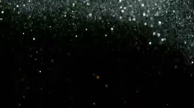 Siyah arka plan üzerine süper ışıltılı, yavaş gümüş parçacıkları. Odak sığ derinliği. Yüksek hız sinema kamerası, 1000 fps üzerinde filme.