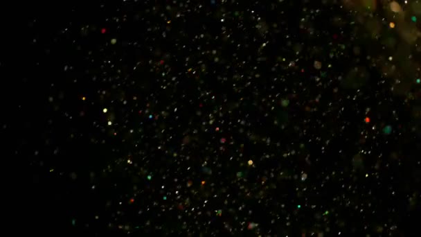 Mouvement super lent de particules colorées scintillantes sur fond noir, faible dof. Filmé sur caméra de cinéma à grande vitesse, 1000 images par seconde .