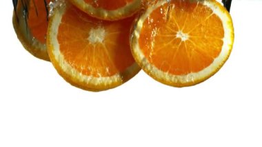 Beyaz arka plan üzerinde izole turuncu dilimler düşen süper yavaş hareket. Yüksek hızlı sinema kamera, 1000 fps filme.