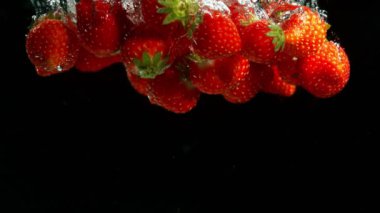 Siyah arka plan üzerinde suya düşen çilek Süper yavaş hareket. Yüksek hızlı sinema kamera, 1000 fps filme.
