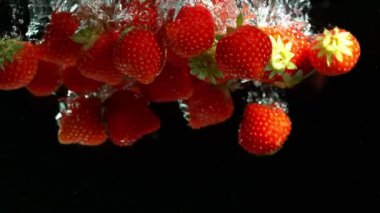 Siyah arka plan üzerinde suya düşen çilek Süper yavaş hareket. Yüksek hızlı sinema kamera, 1000 fps filme.