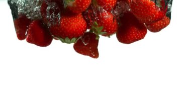 Çileklerin beyaz arka planda suya düşmesi çok yavaş bir hareket. Yüksek hızlı sinema kamerası, 1000 fps..