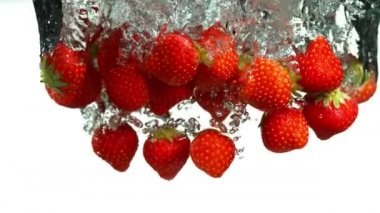 Çileklerin beyaz arka planda suya düşmesi çok yavaş bir hareket. Yüksek hızlı sinema kamerası, 1000 fps..