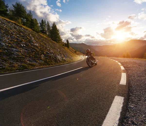 Motorcykelförare kör i alpint landskap. — Stockfoto